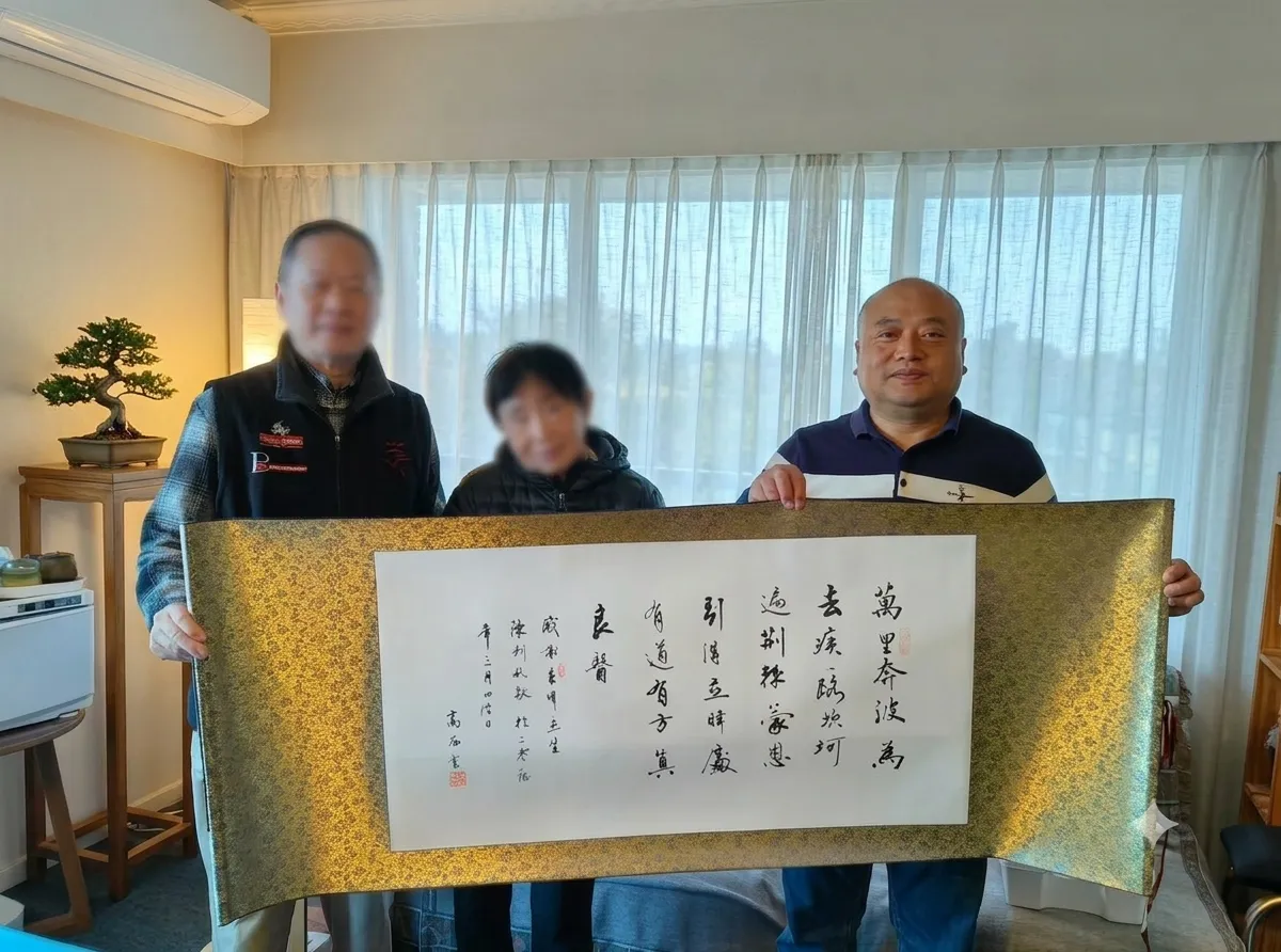 Mrs Q and family with Levi holding a framed Chinese calligraphy work in the clinic